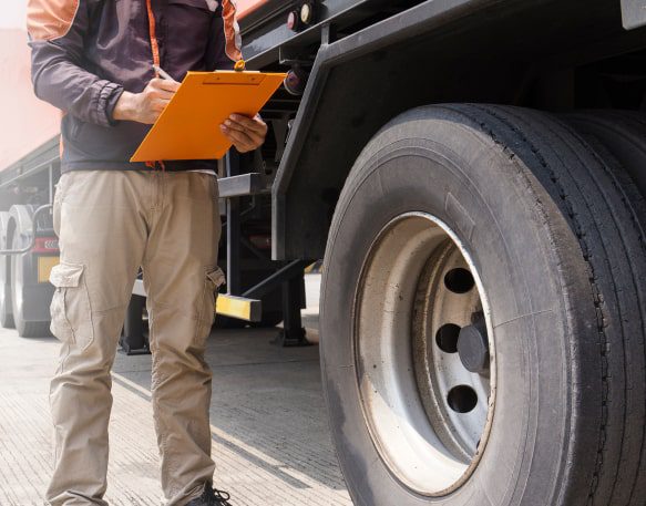 A Roadside Inspector Checks The Outside Of A Truck Min