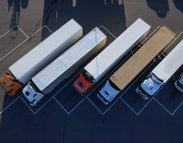 A Row Of Trucks Sits In A Parking Lot Min