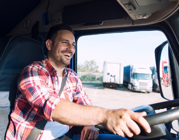 A Truck Driver Pulls Out Of A Parking Lot With A Smile On His Face Min