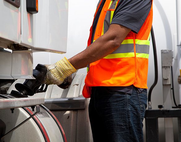 A truck driver refills their truck with discounted fuel thanks to their fuel card