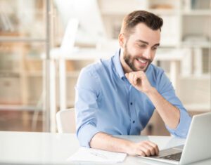 Freight broker smiling while working on his laptop