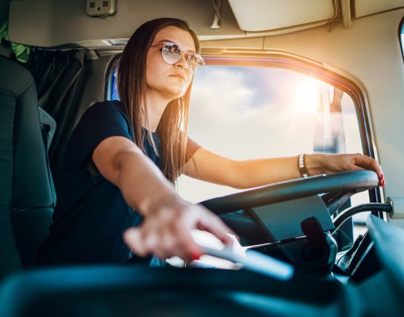 A new truck driver sits behind the wheel of her truck.