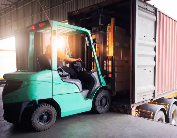 Forklift tractor loading package boxes into a freight truck at a warehouse.