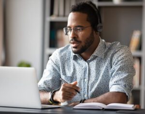Broker-sitting-at-his-desk-working-and-writing-in-notepad.