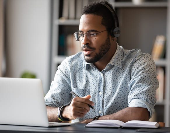 Broker-sitting-at-his-desk-working-and-writing-in-notepad.