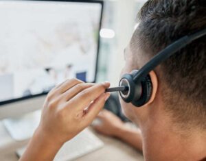 A broker man wearing a headset is sitting in front of a computer