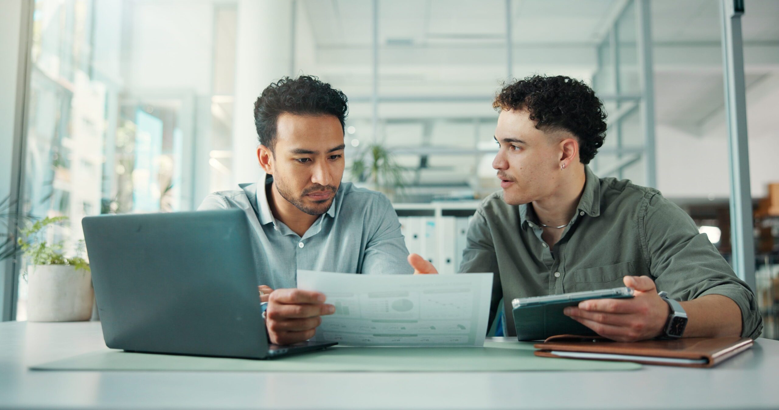Two freight shipping professionals looking at freight data on a piece of paper discussing how to improve it