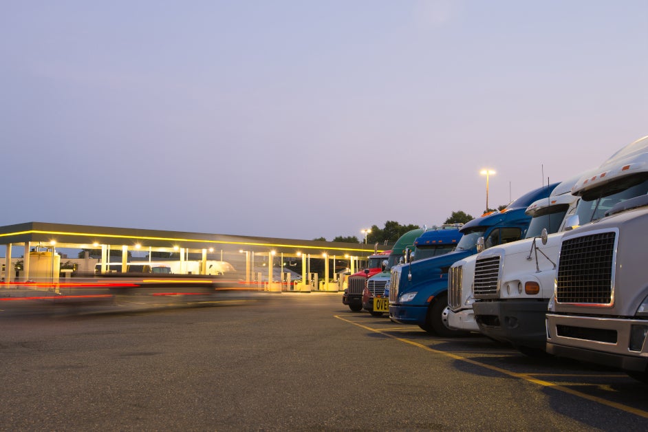 Vehicles standing in a gas station parking lot.