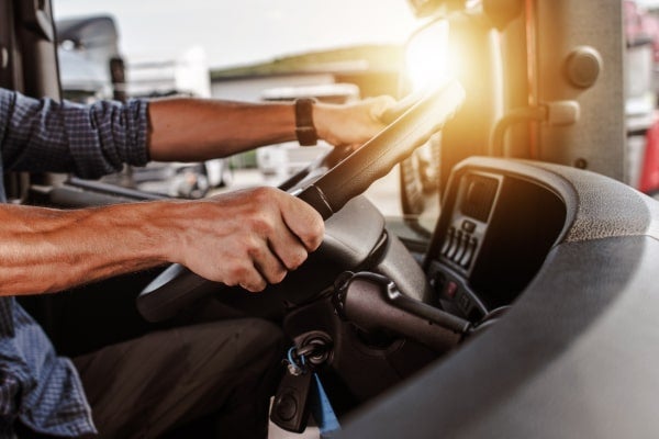 A driver sits behind the wheel of their truck.