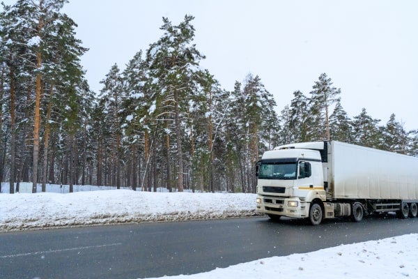 A truck drives down a highway in winter.