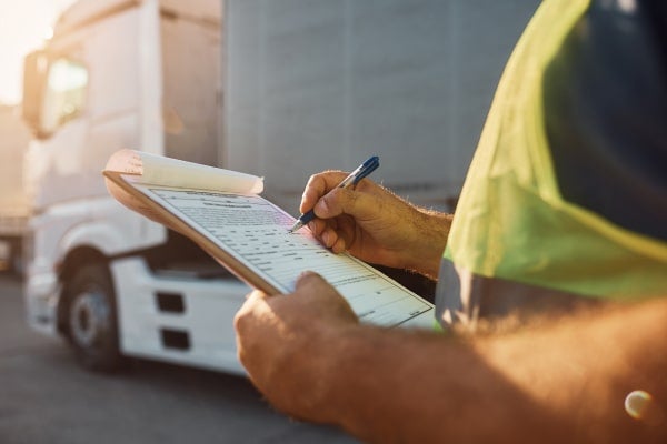 A trucker writes on a clipboard.