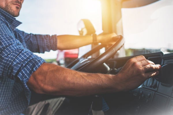 A long-haul trucker sits behind the wheel of his truck.