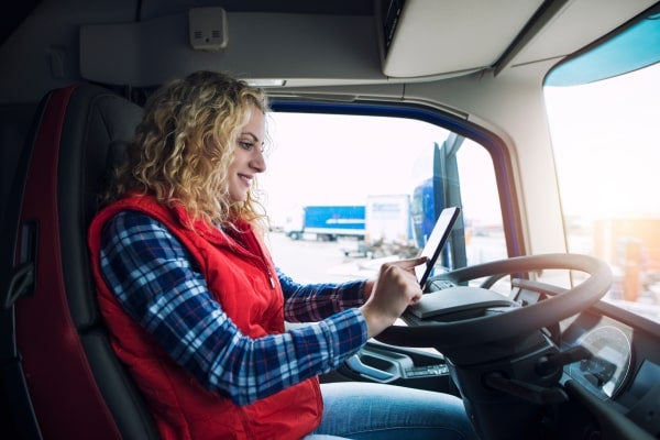 A truck driver uses her truck driver app.