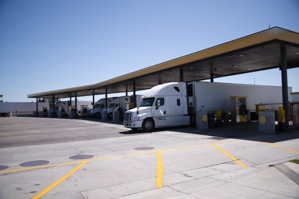 Semi trucks sitting in ports at a trucking gas station.