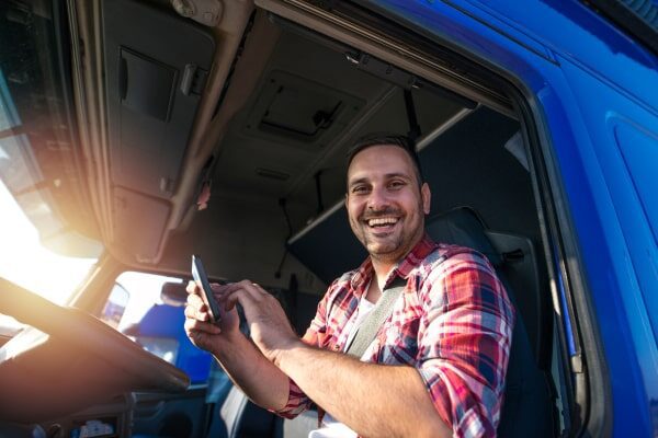 Truck driver smiling at camera as he completes a trucking job.